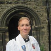 St Mary's Oxenhope priest in charge Reverend Nigel Wright outside the church