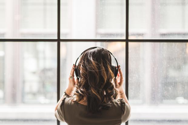 Keighley News: A woman listening to music on her headphones. Credit: Canva