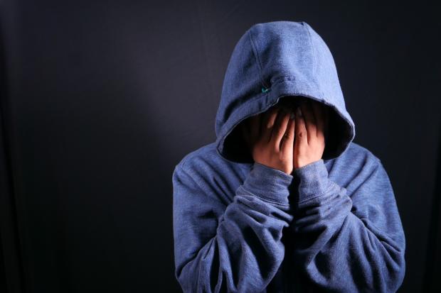 Keighley News: A person touching their face wearing a blue hoodie. Credit: Canva